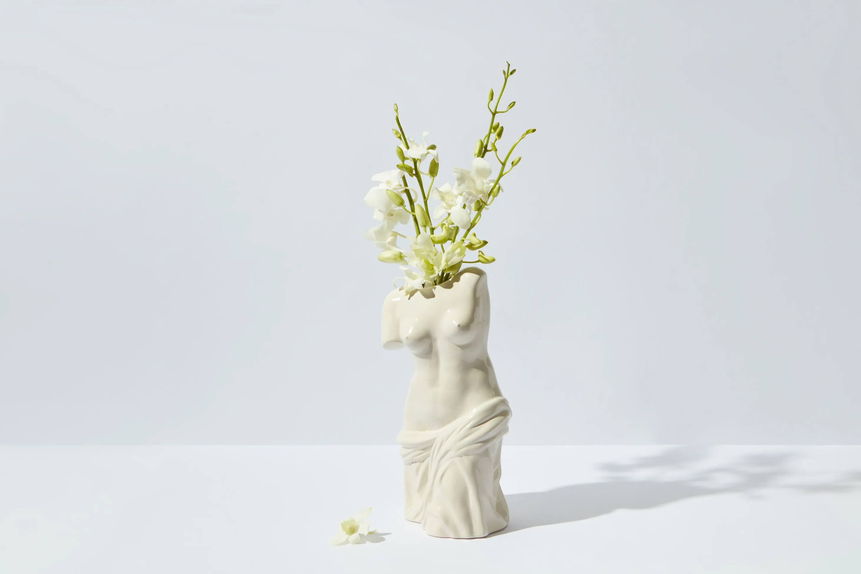 Artistic statue vase with white flowers.