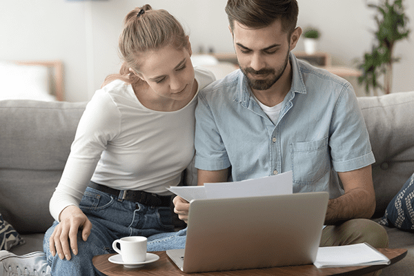 couple looking at paperwork in front of laptop