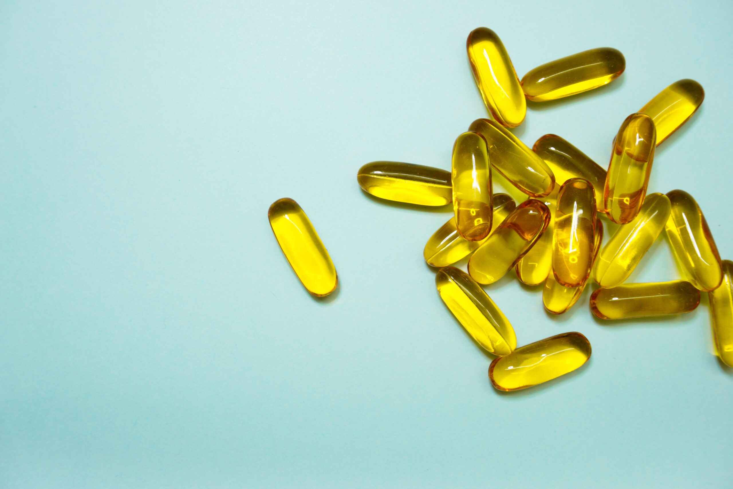 Yellow fertility supplement capsules on a pale teal background